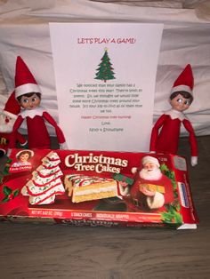 two elfs are sitting next to a christmas tree and some cookies on the table