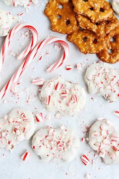 some candy canes and cookies on a white surface with sprinkles around them