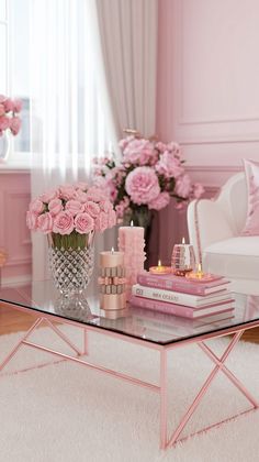 a glass table with pink flowers and candles on it in front of a white couch