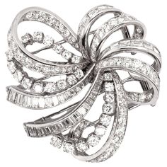 Introducing an absolutely stunning diamond double-clip brooch by the Parisian jewellery house, Boucheron, exquisitely crafted in luxurious 18ct white gold. This wonderful brooch is intricately designed to resemble a stylised swirling bow, with multiple ribbons that elegantly loop and twist in a dynamic, flowing pattern. Each delicate ribbon is masterfully inlaid with a fantastic array of round brilliant cut and baguette cut diamonds, expertly set to maximise their sparkle and light reflecting properties. The striking diamonds vary in size, creating a mesmerising depth and texture across the brooch and they’re estimated to weight approximately 6.50ct combined. This clever brooch is designed with two clips integrated at the back, so you can separate it into two asymmetric pieces and wear the Diamond Brooches With Brilliant Cut In Fine Jewelry Style, Diamond Brooch With Brilliant Cut, Fine Jewelry Diamond Brooch With Brilliant Cut, Luxury Diamond Brooches In White Gold, Diamond Brooches In Brilliant Cut White Gold, Luxury Platinum Brooches, Luxury White Gold Diamond Brooches, Platinum White Gold Fine Jewelry Brooch, White Gold Diamond Brooch With Brilliant Cut