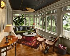 a living room with lots of windows and furniture on the wood floored flooring