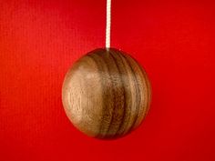 a wooden ornament hanging on a red wall with white string attached to it