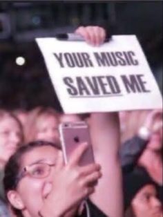 a woman holding up a sign that says your music saved me