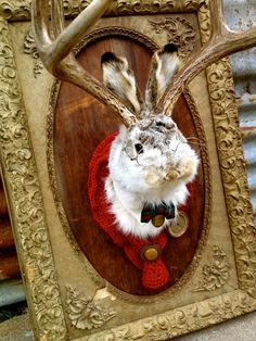 a rabbit wearing a red sweater and antlers is in a wooden frame with an ornate design