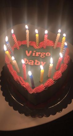 a heart shaped cake with lit candles in the shape of a virgo baby on it