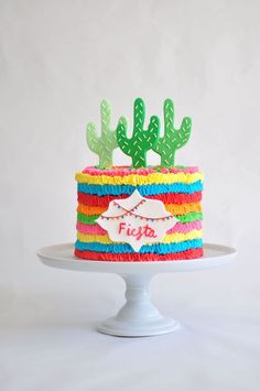 a cake decorated with colorful frosting and cactus decorations