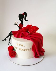 a white cake decorated with red roses and an image of a woman sitting on top