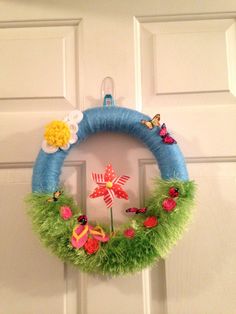 a blue wreath with flowers and butterflies hanging on the front door to decorate it for someone's special occasion