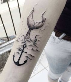 a woman's arm with an anchor and whale tail tattoo on the left forearm