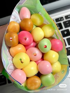 a person holding a bag full of fake fruit in front of a laptop computer keyboard