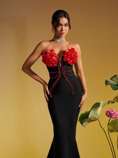 a woman in a black dress with red flowers on her shoulders and neckline, posing for the camera