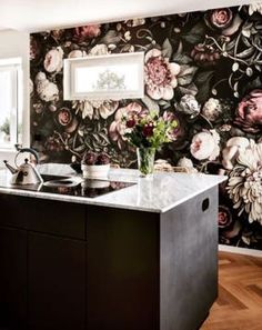 a kitchen with floral wallpaper and black cabinets