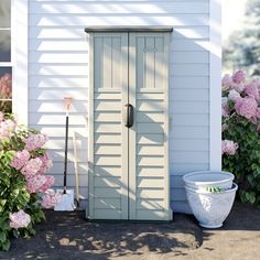 a white house with pink flowers in front of it and a potted plant next to the door