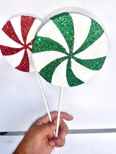 two lollipops with green and red glitter on them