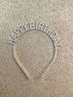 the word happy birthday written in silver glitter on a carpeted surface with a headband