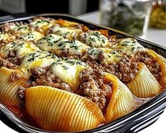 a casserole dish filled with stuffed shells and ground beef, topped with cheese