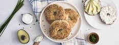 three bagels are on a plate next to an avocado and sour cream