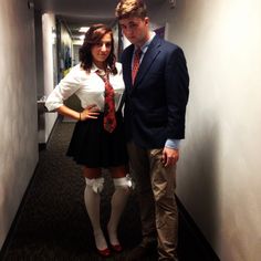 a man and woman standing next to each other in an office hallway wearing dress clothes