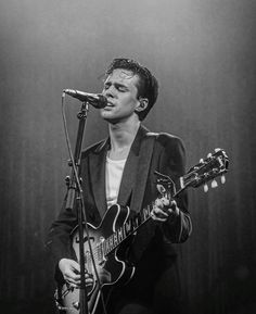 a man that is playing a guitar in front of a microphone