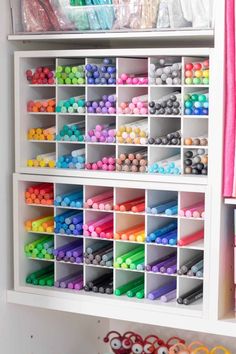 a white shelf filled with lots of different colored crayons and other craft supplies