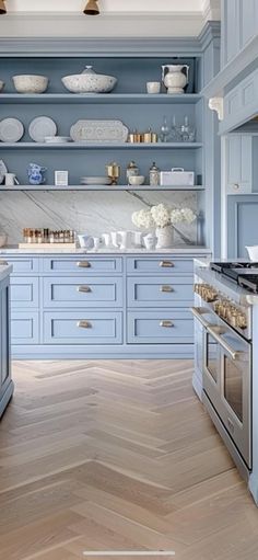 a large kitchen with blue cabinets and white counter tops on the walls, along with wooden flooring