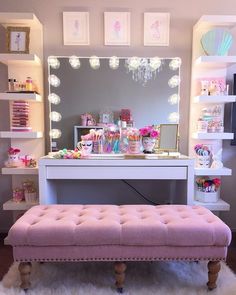 a pink bench sitting in front of a mirror on top of a table next to a dresser