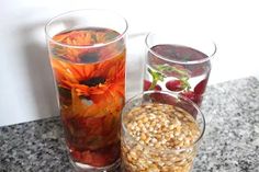 three glasses filled with different types of flowers and grains next to each other on a table