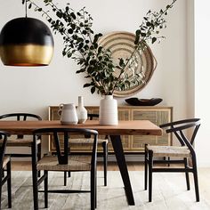 a dining room table and chairs with plants in vases next to it on the wall