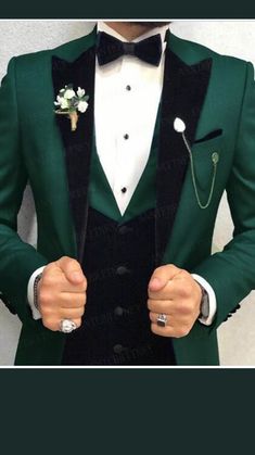 a man wearing a green suit and bow tie with his hands in his pockets,