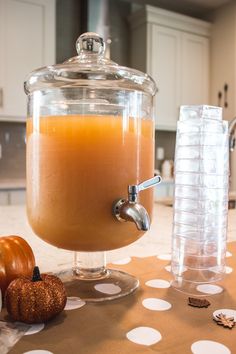 there is a glass jar with liquid in it on the table next to pumpkins