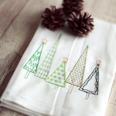 three pine cones are sitting on top of two napkins that have christmas trees drawn on them