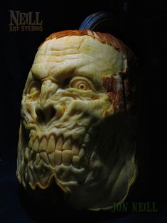 a carved pumpkin with an evil face on it's head and the words hell art studios