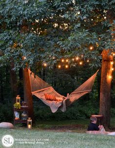 a person laying in a hammock with lights strung from the trees