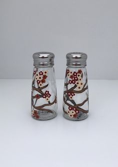 two glass salt and pepper shakers decorated with flowers