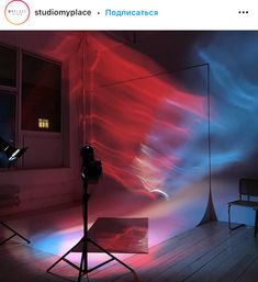 a photo studio with red, blue and white light coming from the window behind it