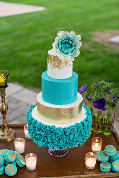 a blue and white cake sitting on top of a table next to cupcakes