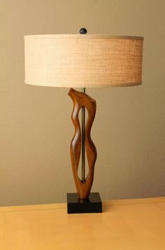 a wooden table lamp sitting on top of a wooden desk next to a white wall