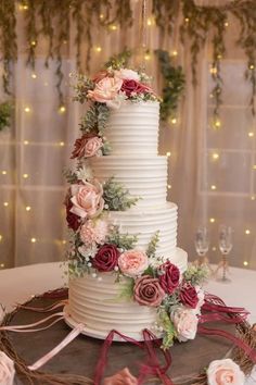 a white wedding cake with flowers on top and ribbons around the edges, sitting on a table