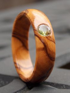 a close up of a wooden ring on a stone surface with a diamond in the center