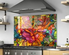 an abstract painting on the wall in a kitchen with stainless steel stove and range hood