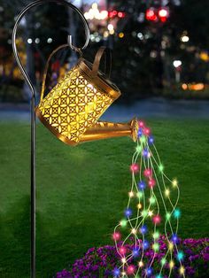 a light up watering can in the shape of a tree with multicolored lights