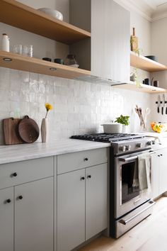 a stove top oven sitting inside of a kitchen next to wooden shelves and counter tops