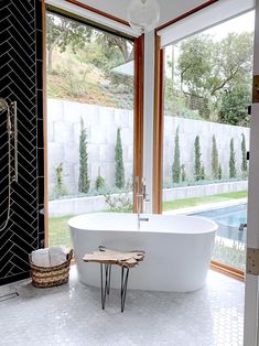 a large white bath tub sitting next to a window in a room with glass doors