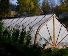 a large white greenhouse sitting on top of a lush green forest covered in lots of trees