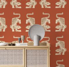 an orange and white wallpaper with zebras on it, next to a cabinet