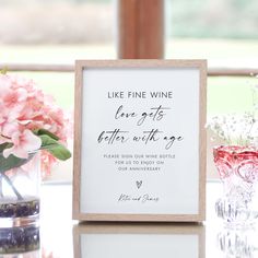 a wooden sign sitting on top of a table next to vases filled with flowers