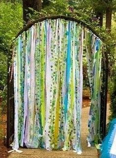 an outdoor wedding ceremony in the woods with colorful drapes and streamers draped over it