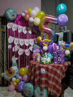 a birthday party with balloons and streamers on the table in front of a number 5 sign