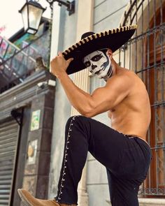 a shirtless man with a skull face paint sitting on top of a skateboard