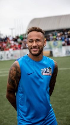 a man standing on top of a soccer field wearing a blue shirt and black shorts